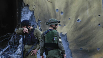 Israeli soldiers walk past houses destroyed by Hamas.