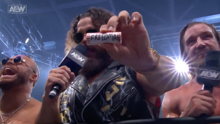 AEW wrestler Juice Robinson holds up a roll of quarters bearing the last name of Maxwell Jacob Friedman.